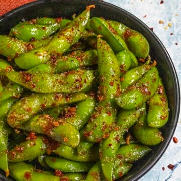 Spicy Edamame served in a bowl with a fiery dressing and chili flakes