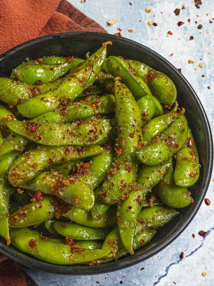 Spicy Edamame served in a bowl with a fiery dressing and chili flakes
