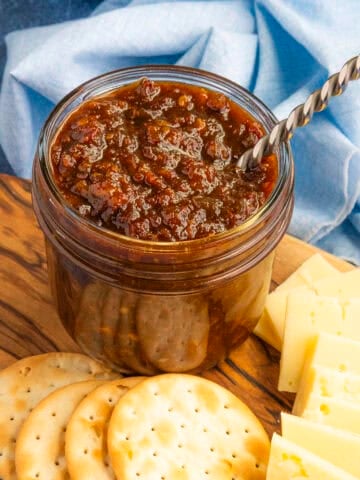 A jar of gooey, delicious bacon jam in a jar with a spoon, ready to serve