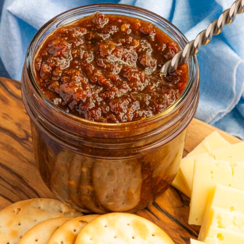 A jar of gooey, delicious bacon jam in a jar with a spoon, ready to serve