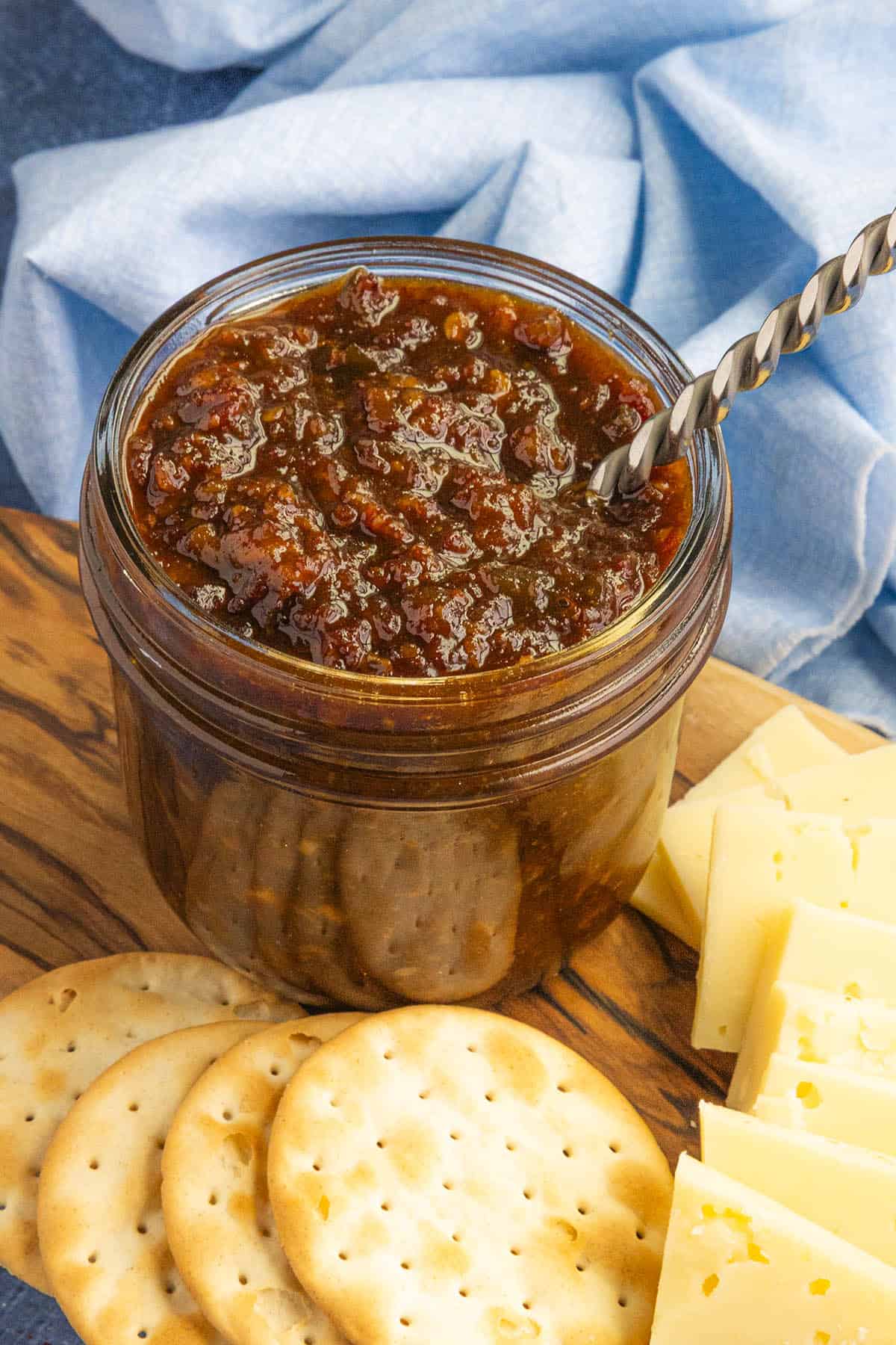 A jar of gooey, delicious bacon jam in a jar with a spoon, ready to serve