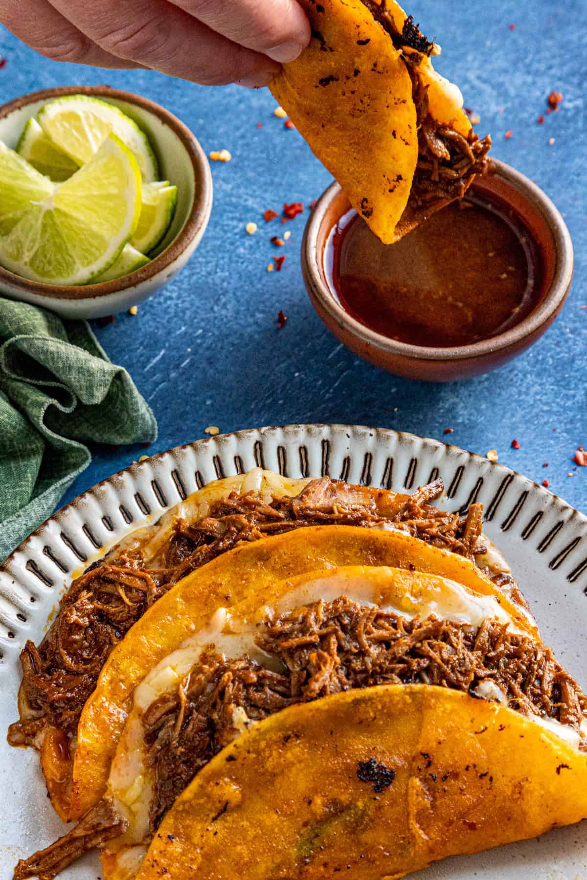 Mike dipping a birria taco into a bowl of juicy birria sauce