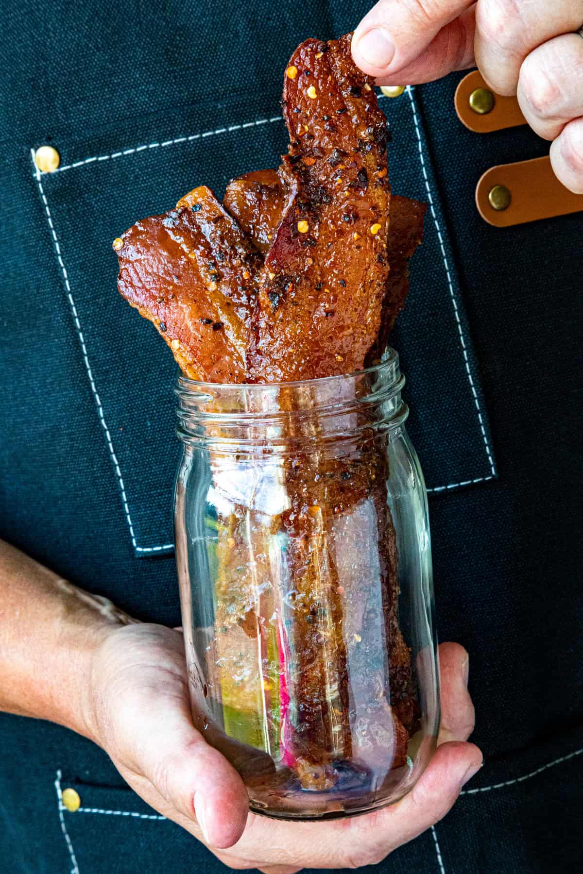 Mike pulling a piece of Candied Bacon from a serving jar