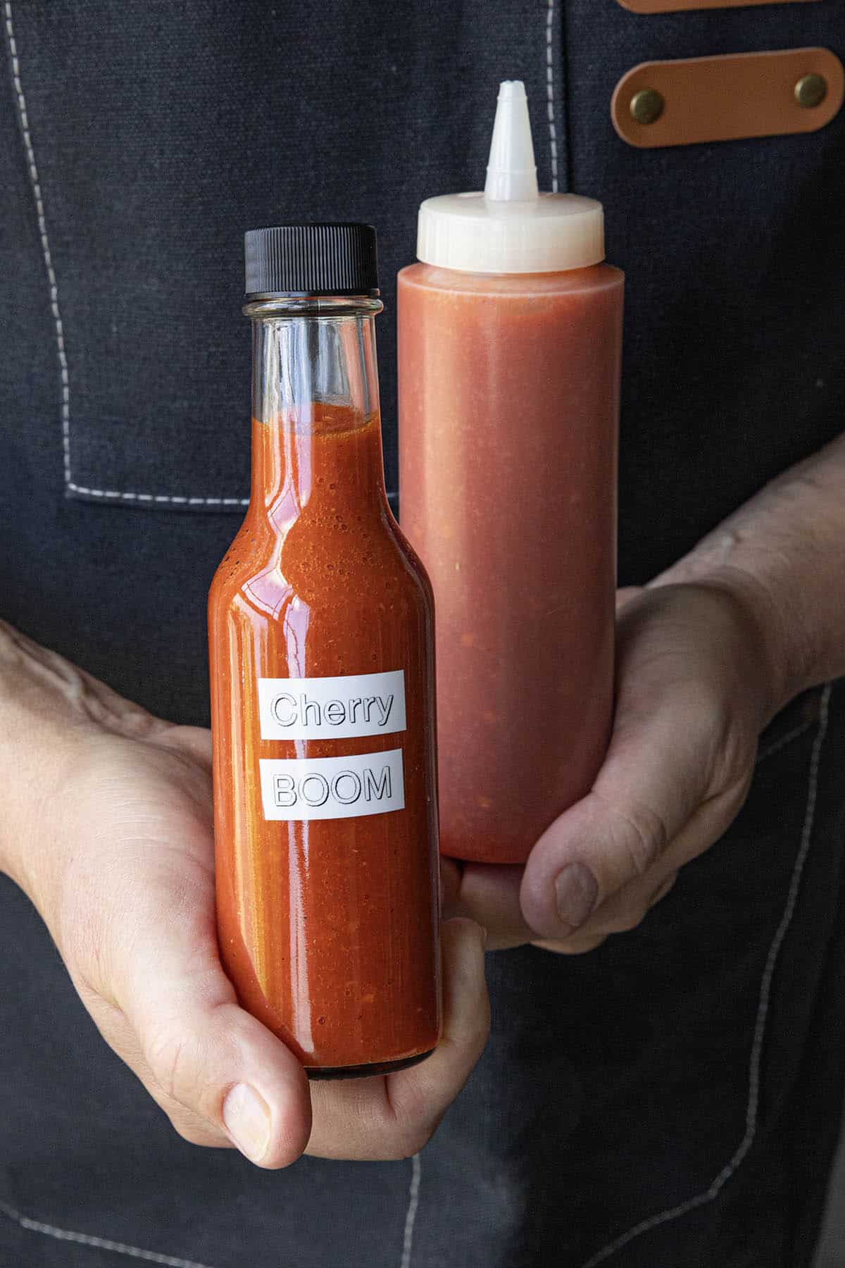 Mike holding 2 bottle of Cherry Bomb Hot Sauce