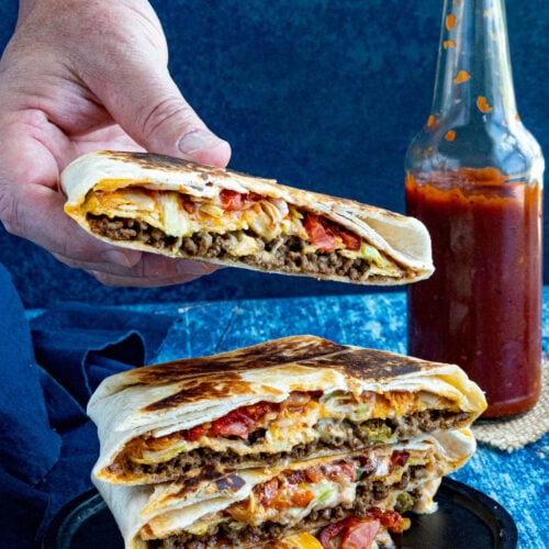 Mike taking a Homemade Crunchwrap Supreme from a stack of them