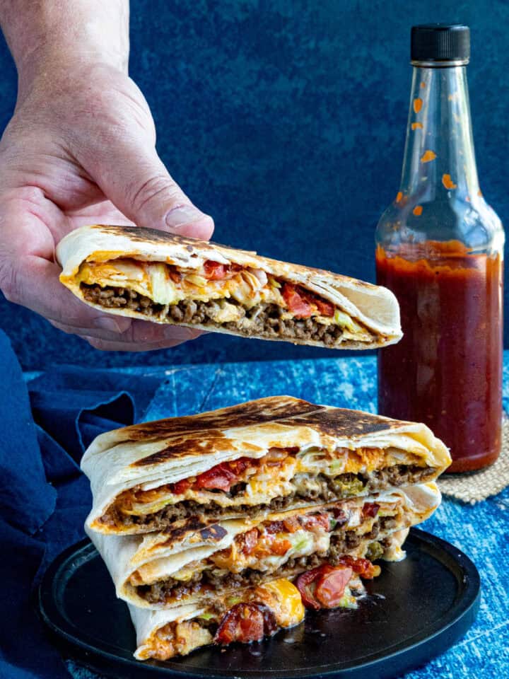 Mike taking a Homemade Crunchwrap Supreme from a stack of them