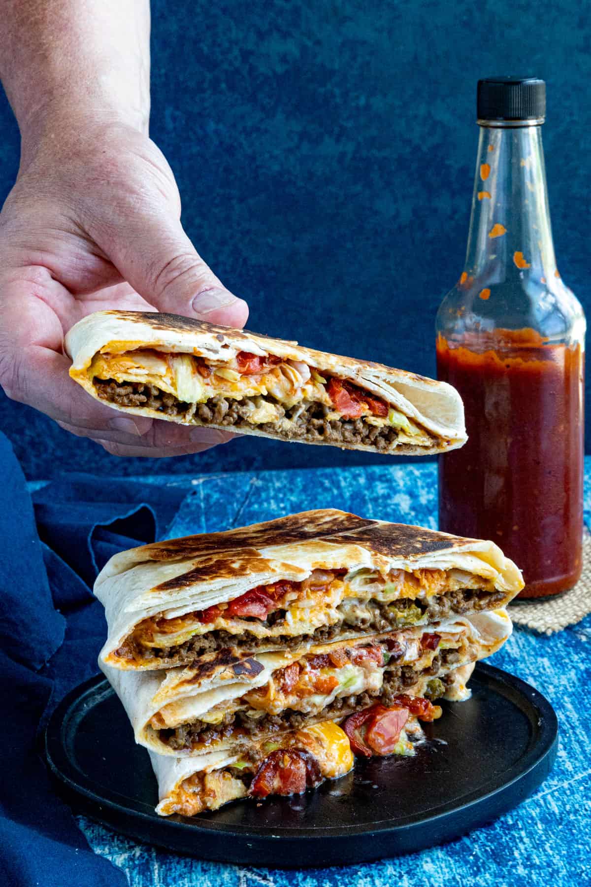 Mike taking a Homemade Crunchwrap Supreme from a stack of them