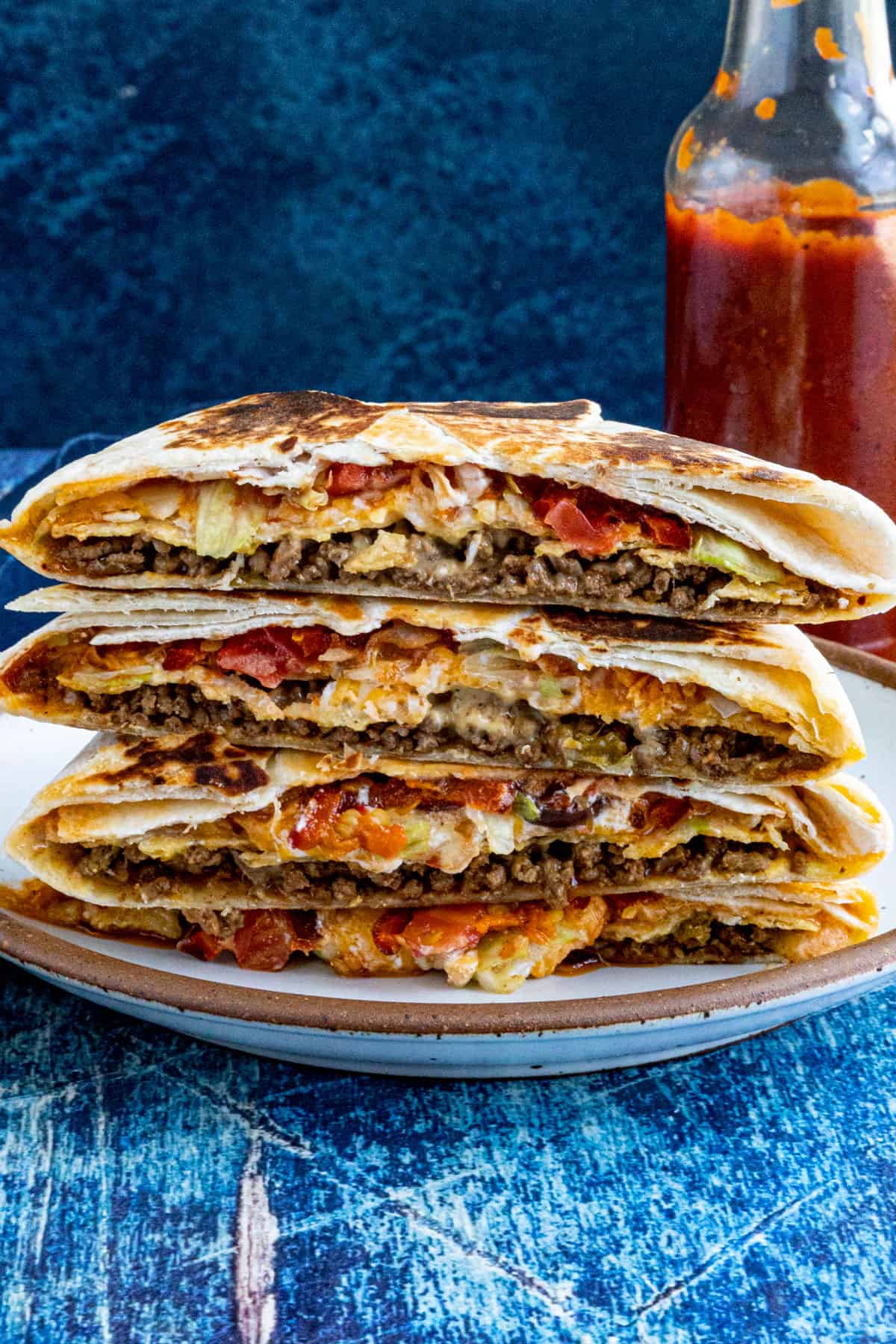 4 Homemade Crunchwrap Supremes stacked up on a plate, ready to serve