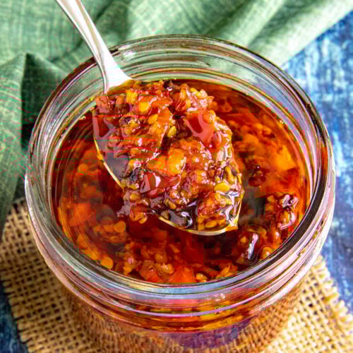 A large spoon of Serrano-Garlic Chili Crunch served from the jar