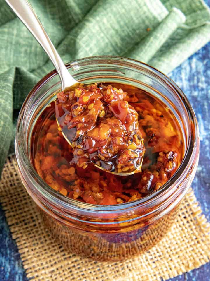A large spoon of Serrano-Garlic Chili Crunch served from the jar