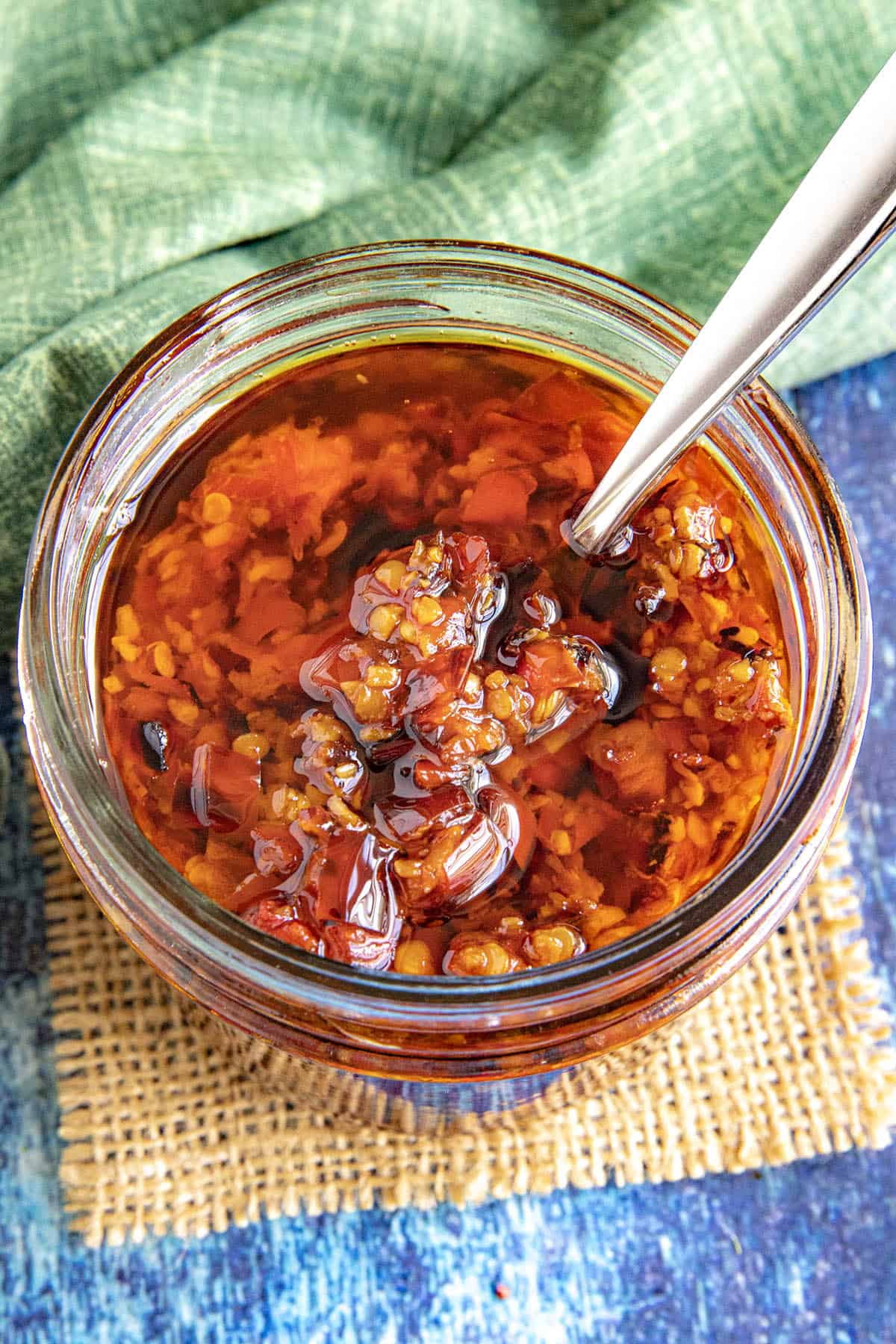 Thick and chunky Serrano-Garlic Chili Crunch in a jar with lots of crispy bits