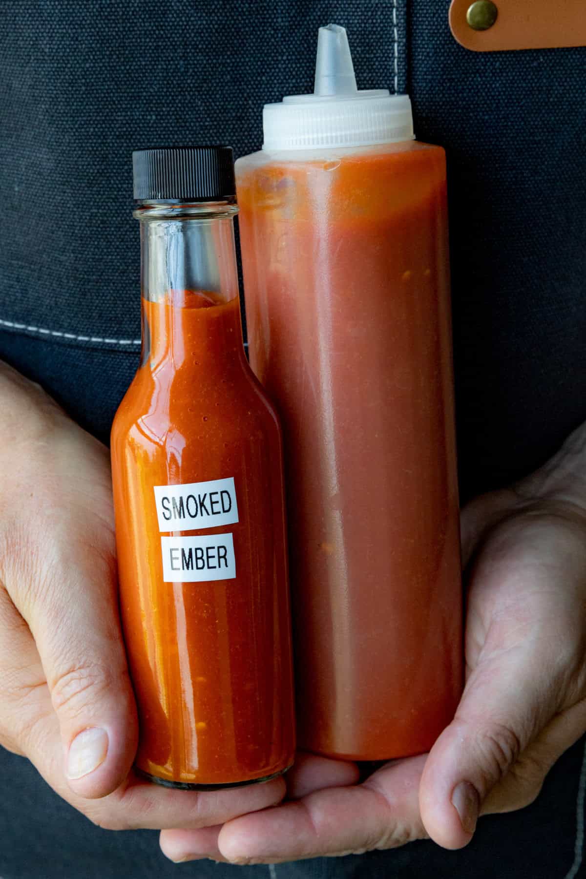 Mike holding a woozy bottle and squeeze bottle of Smoked Chili Hot Sauce (Smoked Ember)