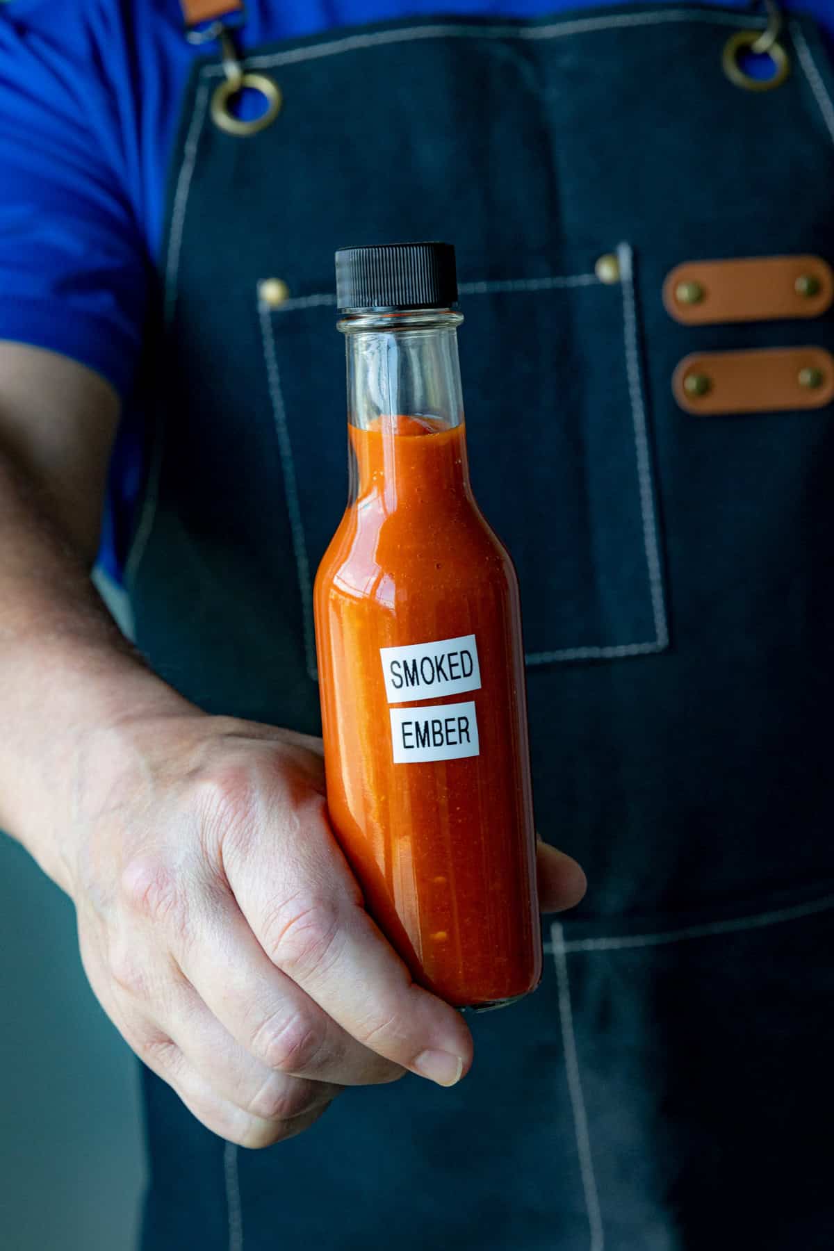 Mike holding a bottle of homemade Smoked Ember Smoked Chili Hot Sauce