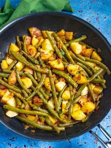 Smothered green beans and potatoes in a pan with smoky bacon