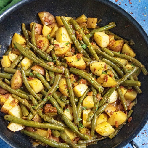 Smothered green beans and potatoes in a pan with smoky bacon