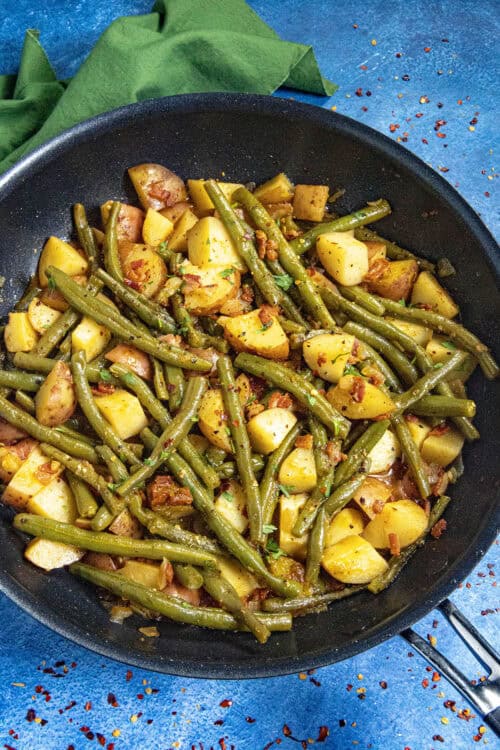 Smothered green beans and potatoes in a pan with smoky bacon