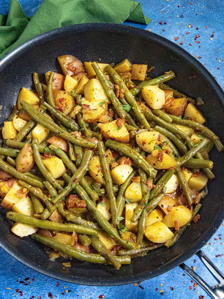 Smothered green beans and potatoes in a pan with smoky bacon