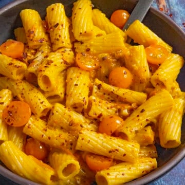 A small bowl filled with penne pasta, served with Tuscan-style Cherry Tomato Pasta Sauce and extra cherry tomatoes