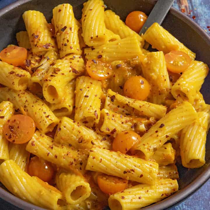 A small bowl filled with penne pasta, served with Tuscan-style Cherry Tomato Pasta Sauce and extra cherry tomatoes