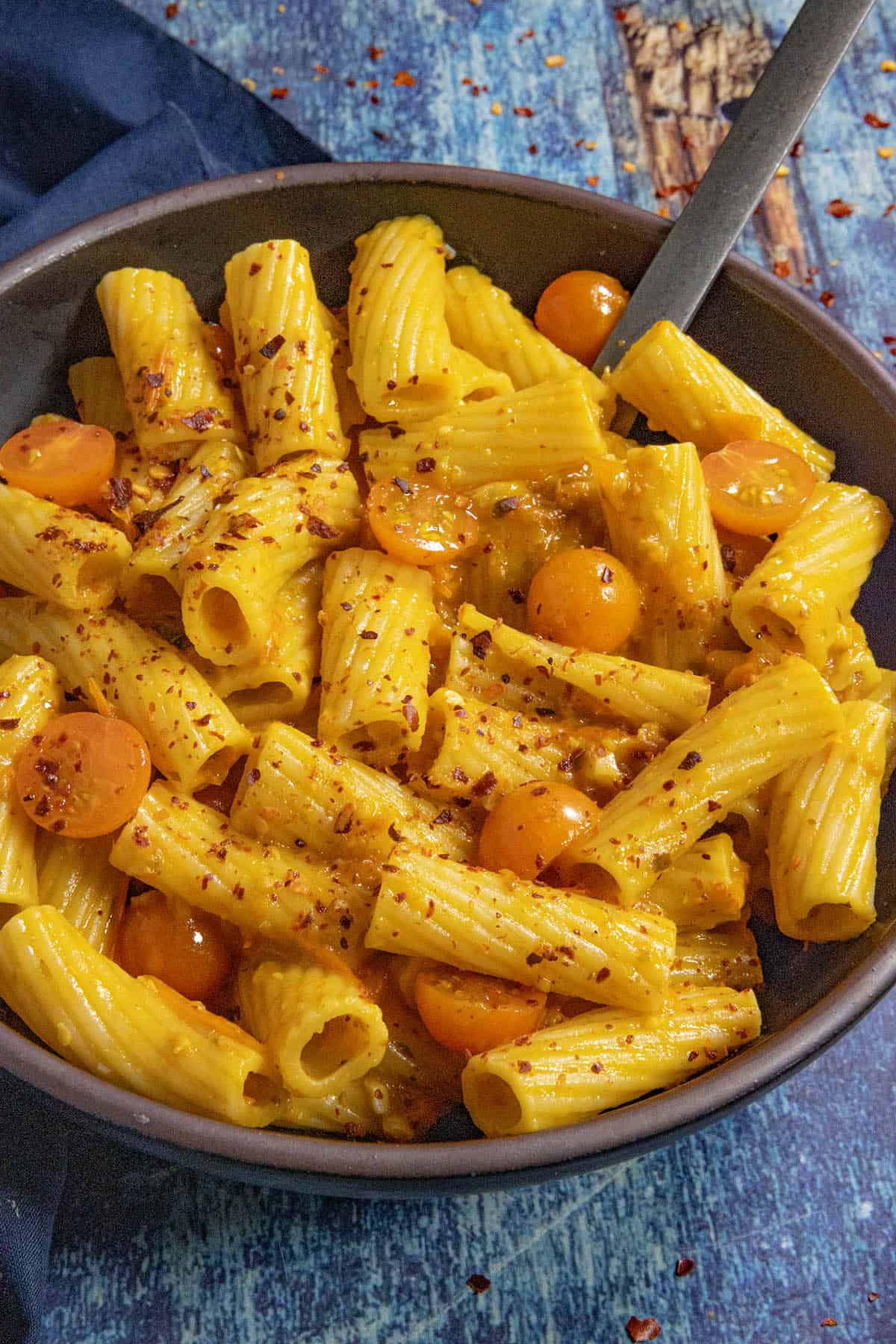 A small bowl filled with penne pasta, served with Tuscan-style Cherry Tomato Pasta Sauce and extra cherry tomatoes