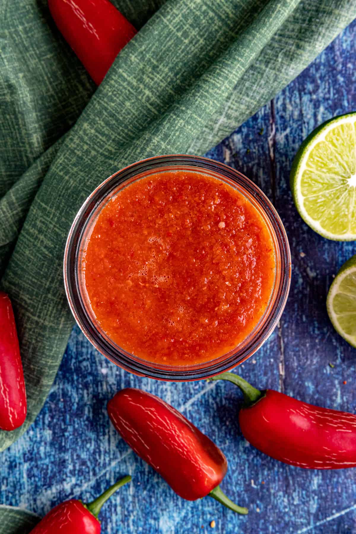 Chili Lime Hot Sauce in a jar, surrounded by fresh chilies