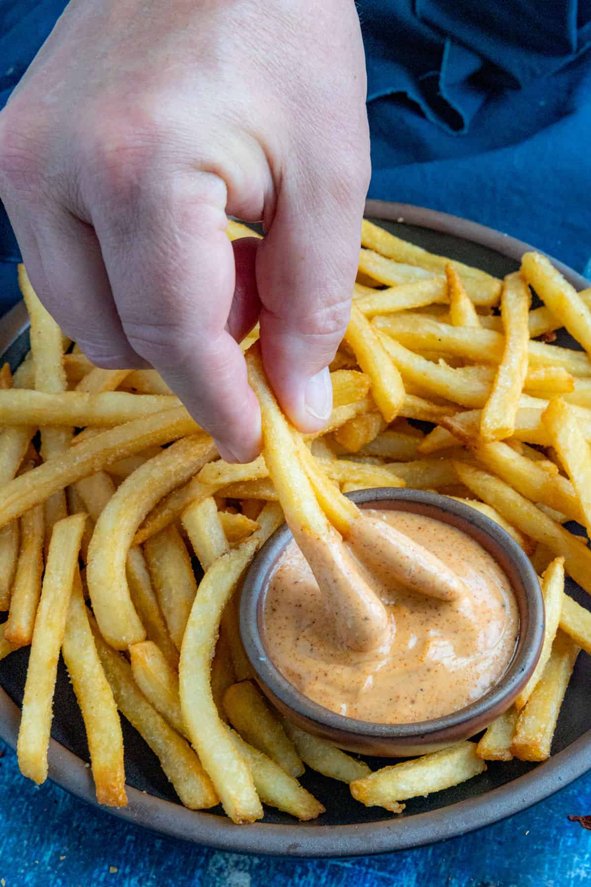 Dipping crispy french fries into a bowl of creamy fry sauce