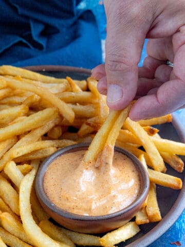 Mike dipping crispy french fries into a bowl of zesty, creamy fry sauce