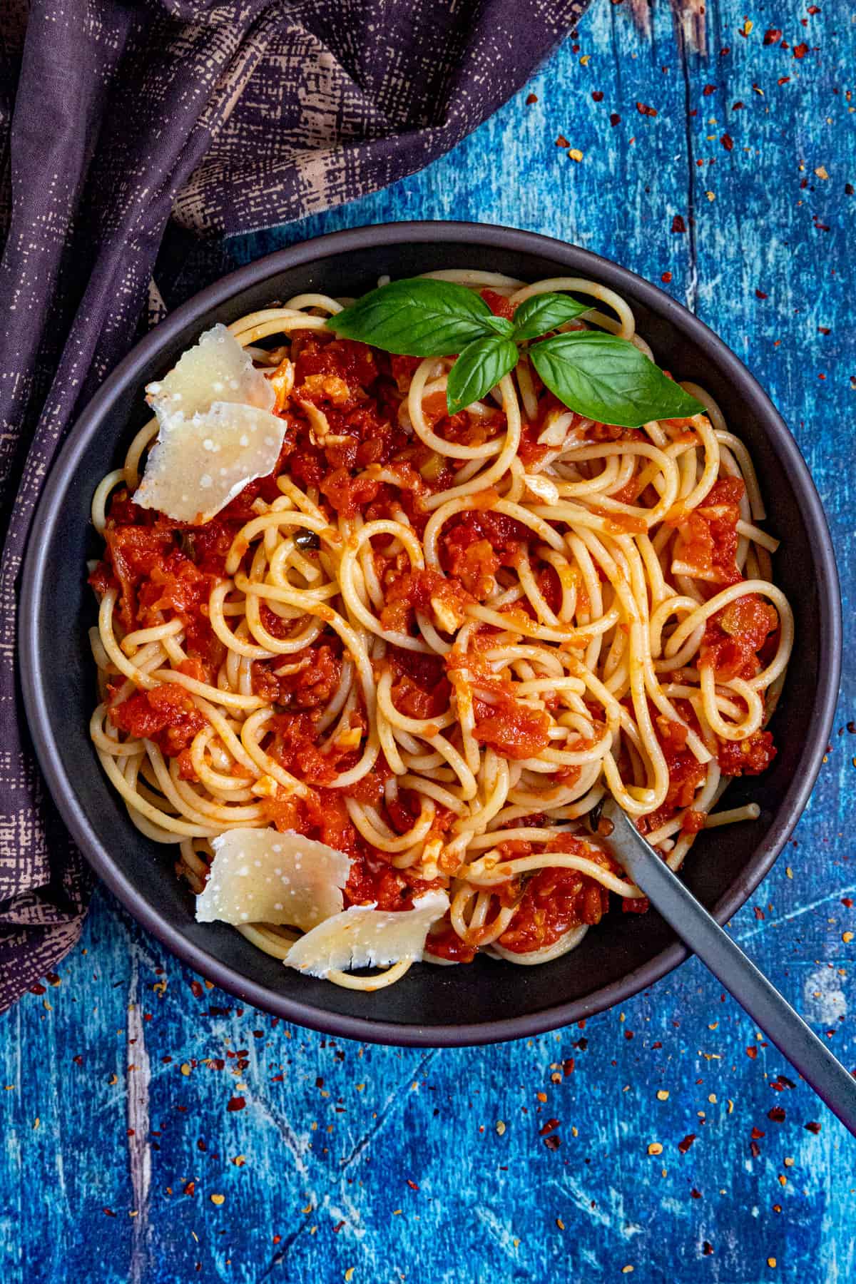 A large bowl of spaghetti tossed in Italian Pomodoro Sauce, with shaved Parmesan cheese and fresh basil