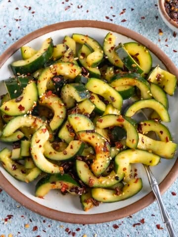 A bowl of Sichuanese Spiced Cucumber Salad (Qiang Huang Gua) garnished with sesame seeds