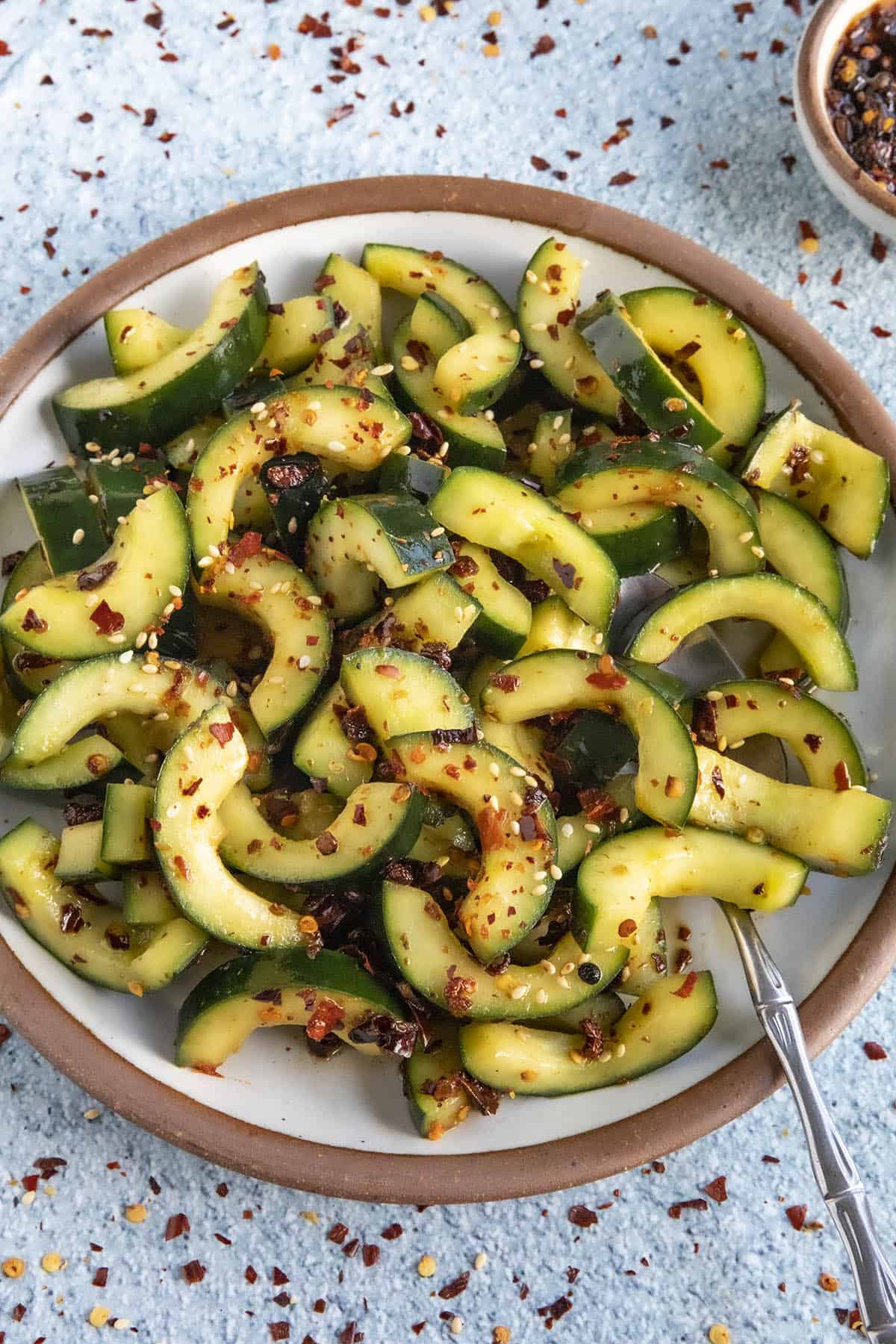 A bowl of Sichuanese Spiced Cucumber Salad (Qiang Huang Gua) garnished with sesame seeds
