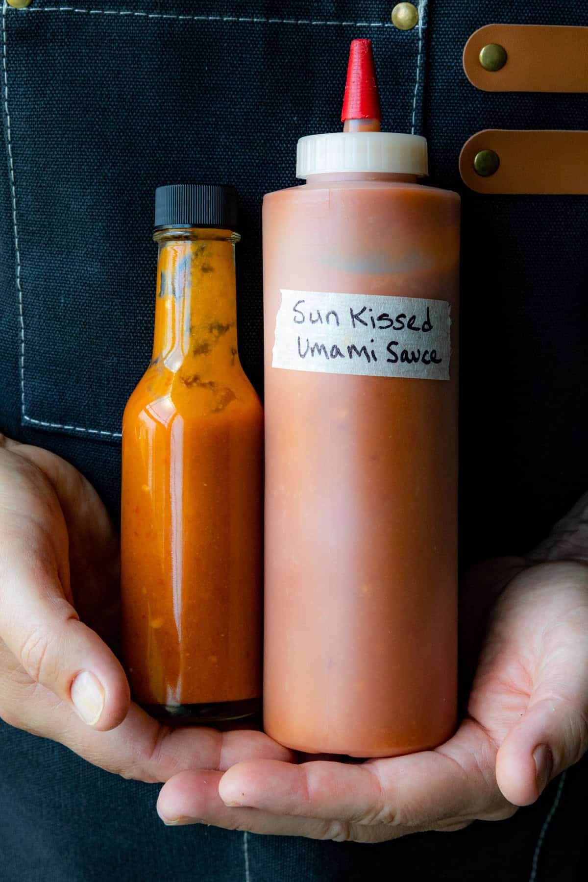 Mike holding 2 bottles of Sun-Kissed Umami Hot Sauce