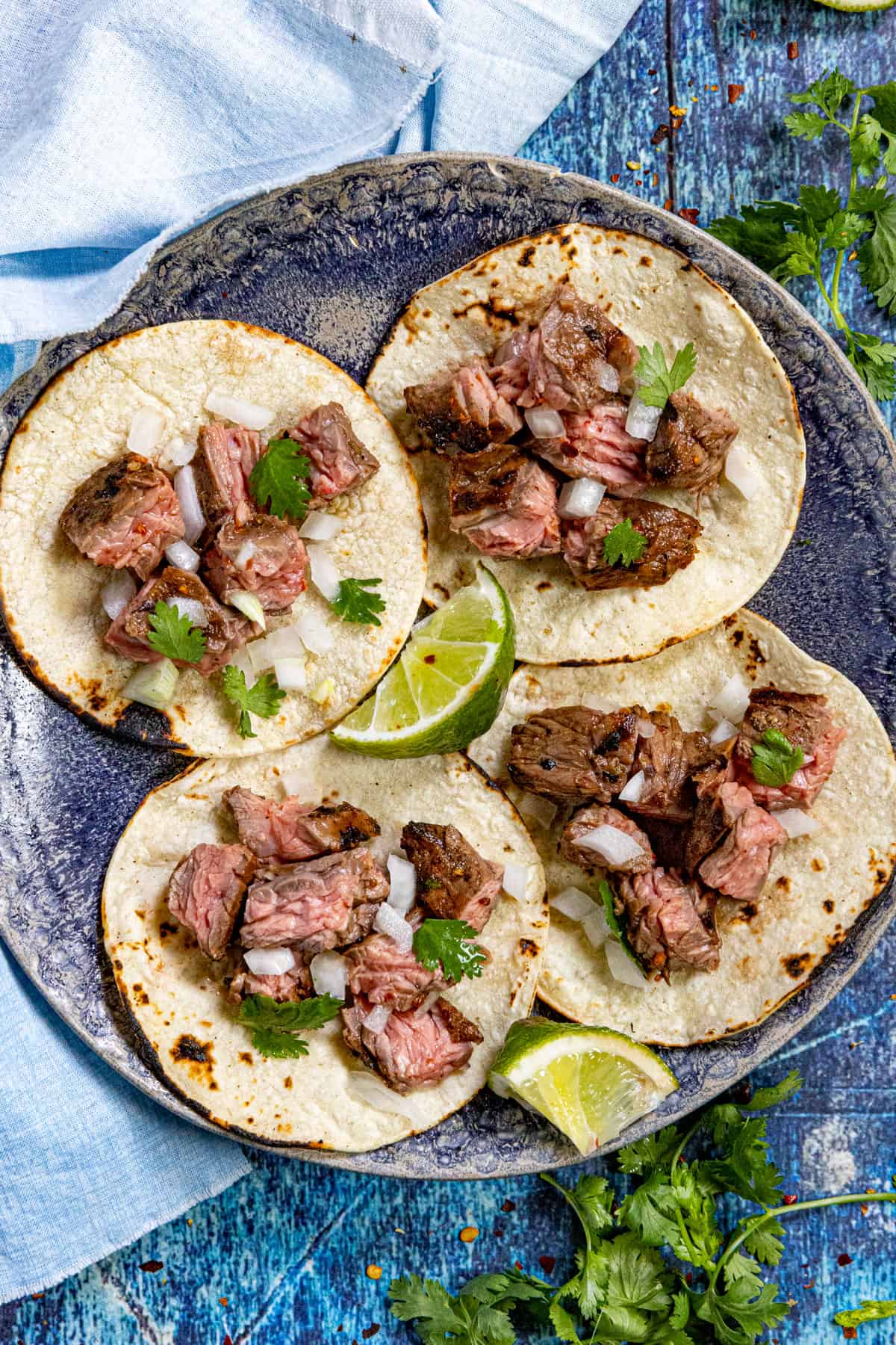 Mexican Skirt Steak (Arrachera) tacos on a plate, garnished with cilantro and onion