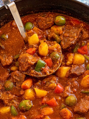 Serving a large ladle full of Beef Caldereta (Filipino Beef Stew) from the pot