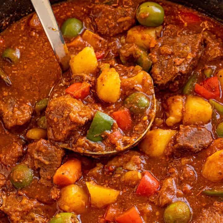 Serving a large ladle full of Beef Caldereta (Filipino Beef Stew) from the pot