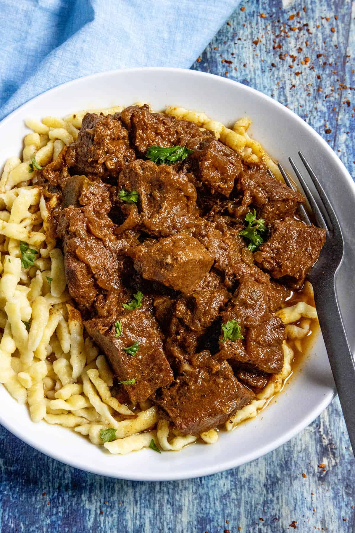 A large bowl of Hungarian Porkolt served over nokedli (noodles), with a fork