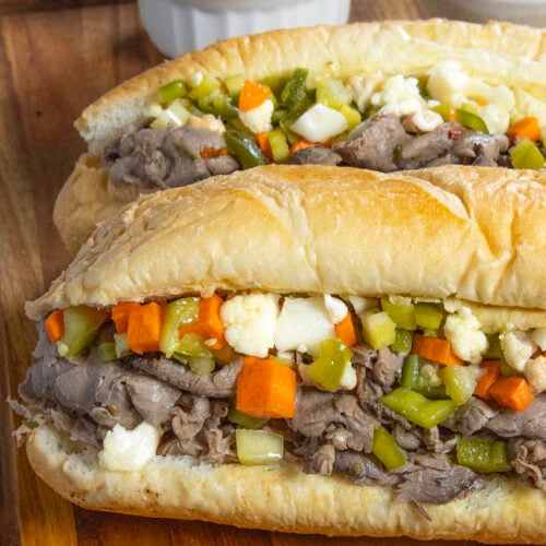 Two Chicago Italian Beef Sandwiches served with extra Chicago-style giardiniera in a bowl and beef jus on the side