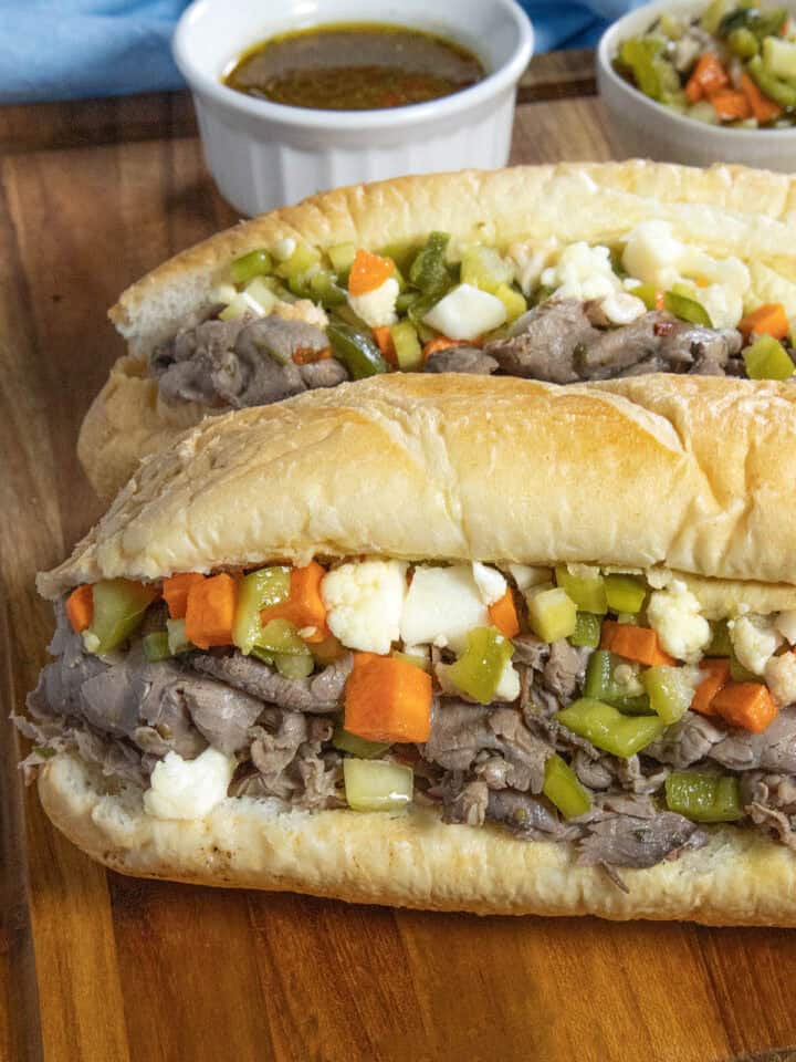Two Chicago Italian Beef Sandwiches served with extra Chicago-style giardiniera in a bowl and beef jus on the side