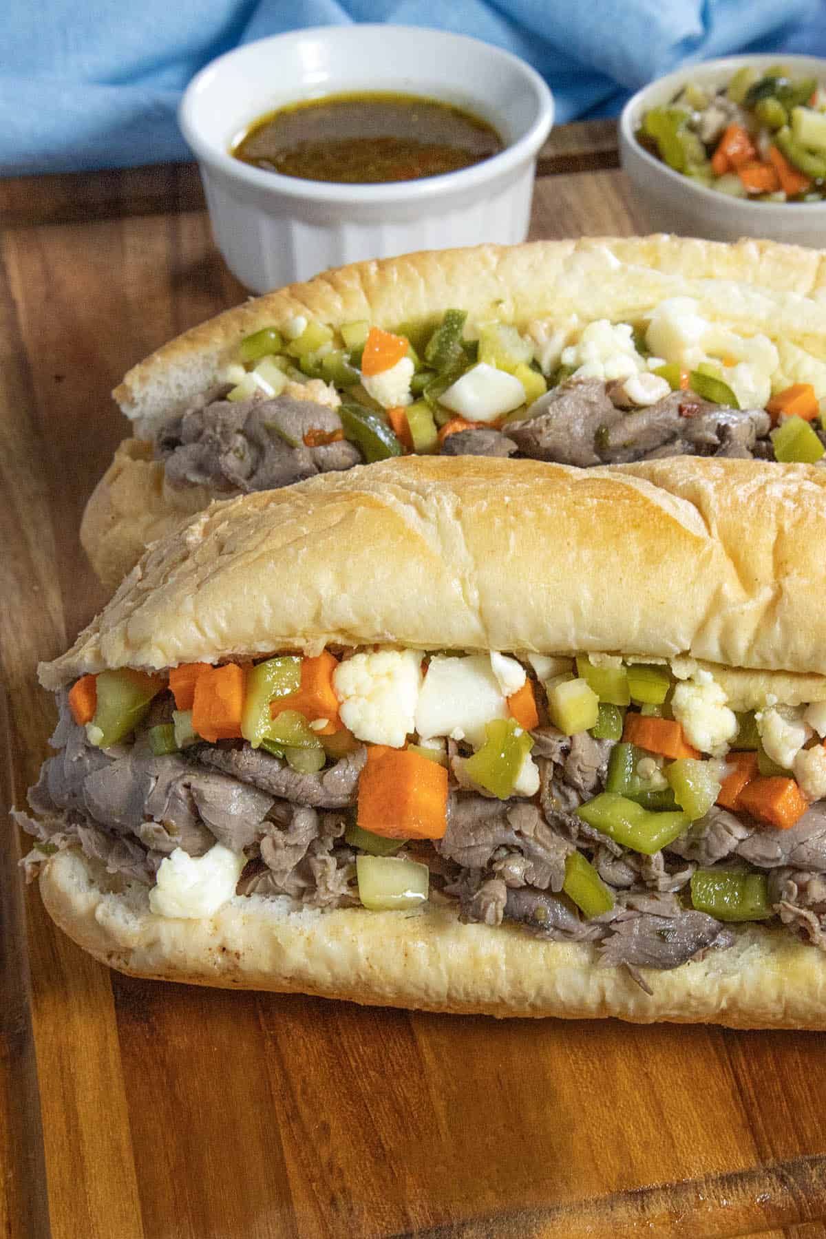 Two Chicago Italian Beef Sandwiches served with extra Chicago-style giardiniera in a bowl and beef jus on the side