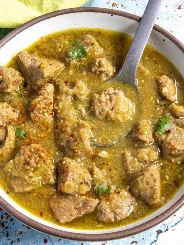 A bowl of chunky Pork Chili Verde, served with a fork