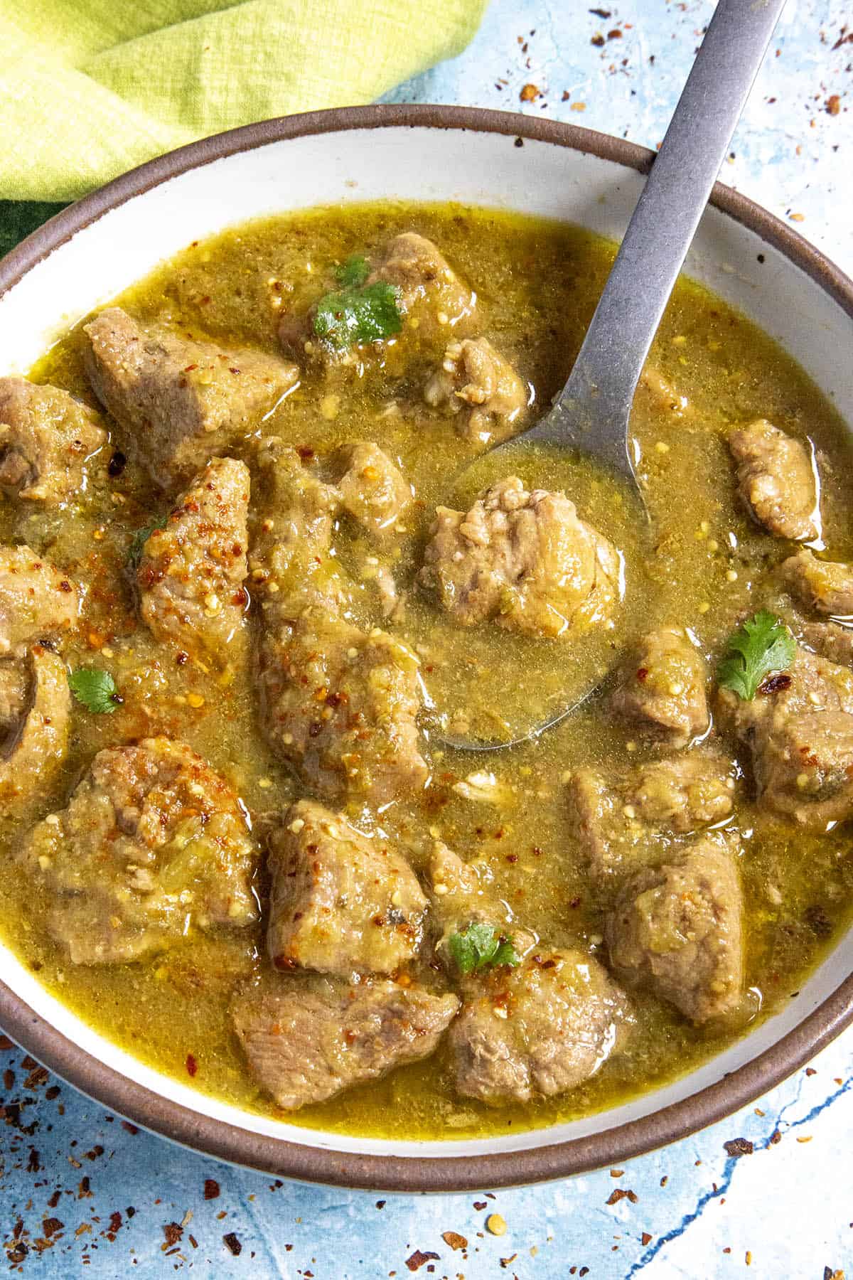A bowl of chunky Pork Chili Verde, served with a fork