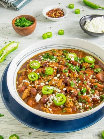 A big bowl of easy-to-make chili topped with sliced jalapenos and crumbly white cheese