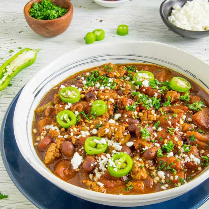 A big bowl of easy-to-make chili topped with sliced jalapenos and crumbly white cheese