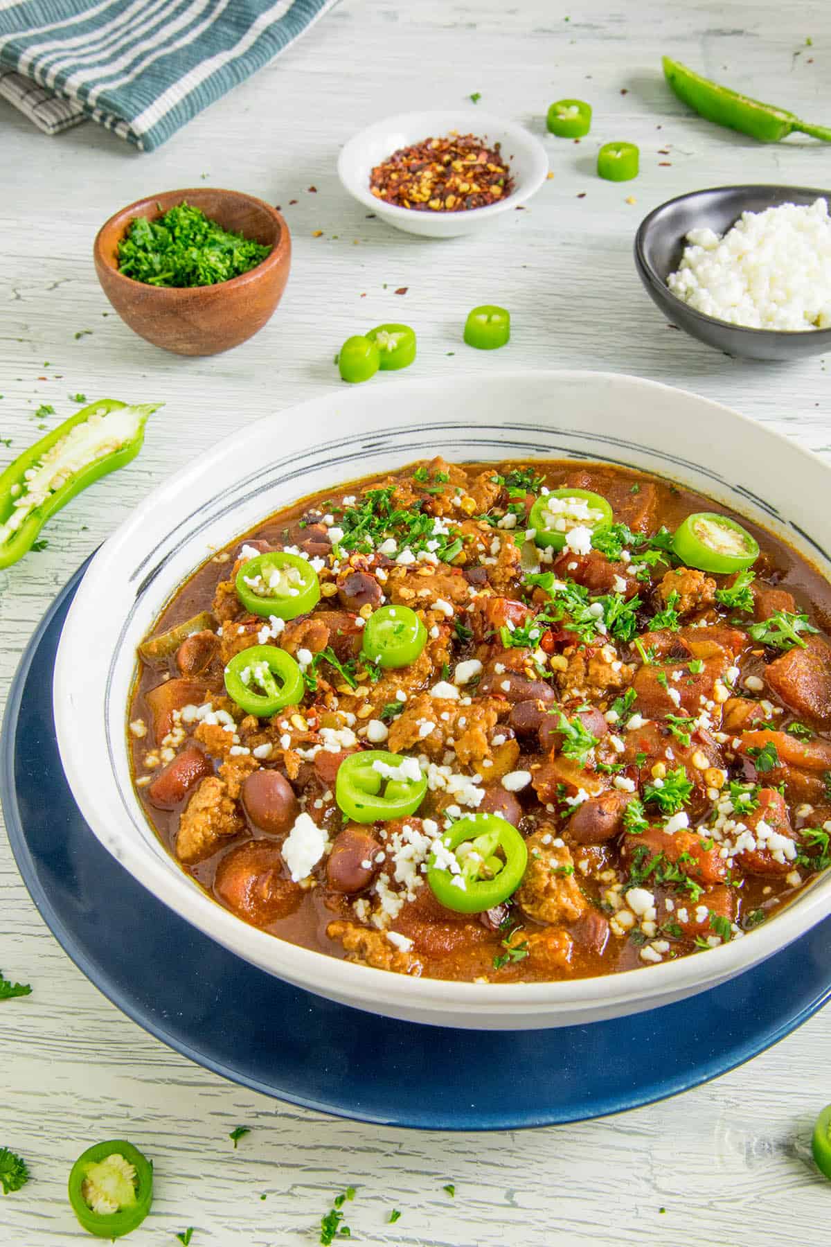 A big bowl of easy-to-make chili topped with sliced jalapenos and crumbly white cheese