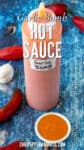 A full bottle of homemade Garlic Bomb Hot Sauce on a table, ready to enjoy