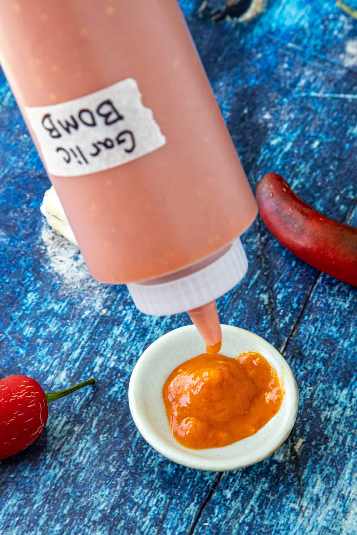 Mike pouring homemade Garlic Bomb Hot Sauce into a bowl from the squeeze bottle