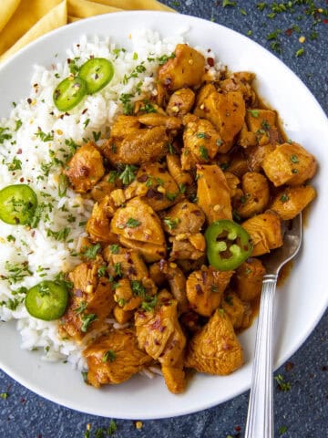 Saucy Gochujang Chicken served on a plate over white rice with sliced chilies for extra heat, quick and easy to make