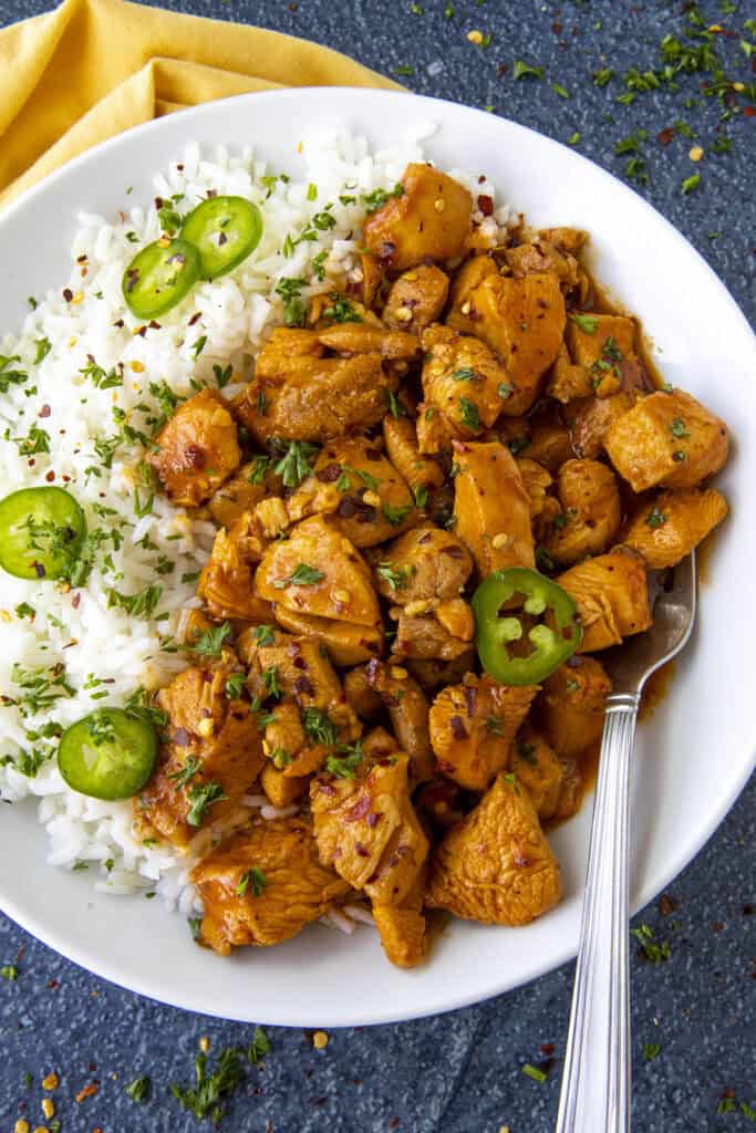 Saucy Gochujang Chicken served on a plate over white rice with sliced chilies for extra heat, quick and easy to make