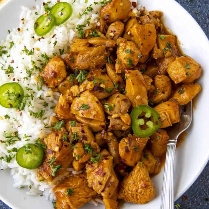 Saucy Gochujang Chicken served on a plate over white rice with sliced chilies for extra heat, quick and easy to make