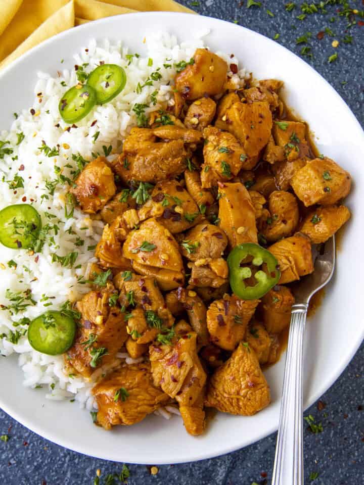 Saucy Gochujang Chicken served on a plate over white rice with sliced chilies for extra heat, quick and easy to make
