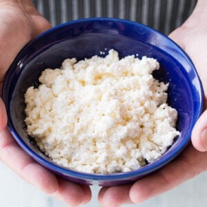 Mike holding a bowl of crumbly fresh Mexican cheese (Homemade Queso Fresco)